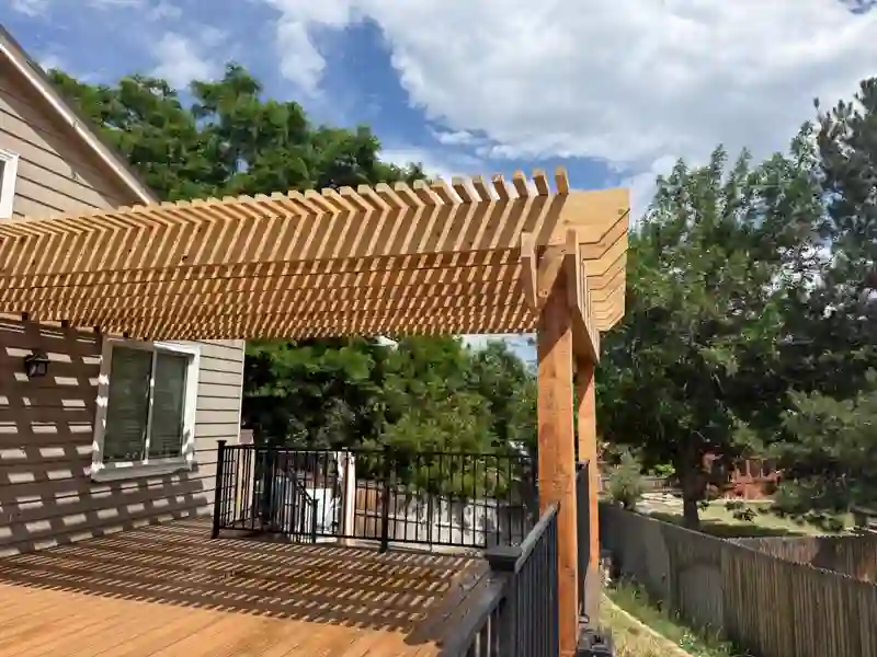 Completed wood deck and pergola with black railings beside the house