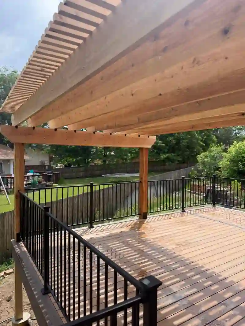 View across a deck and black railings from beneath a timber pergola