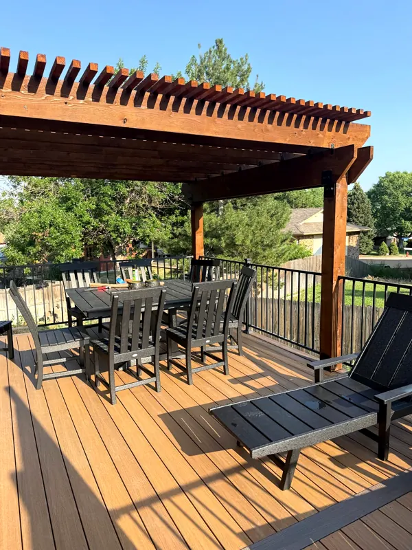 Finished wood deck with timber pergola, black railings and outdoor dining furniture