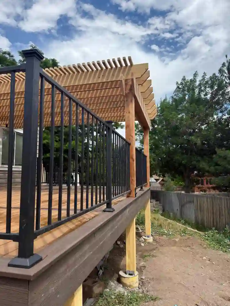 Side view of a raised deck with black railings and a timber pergola