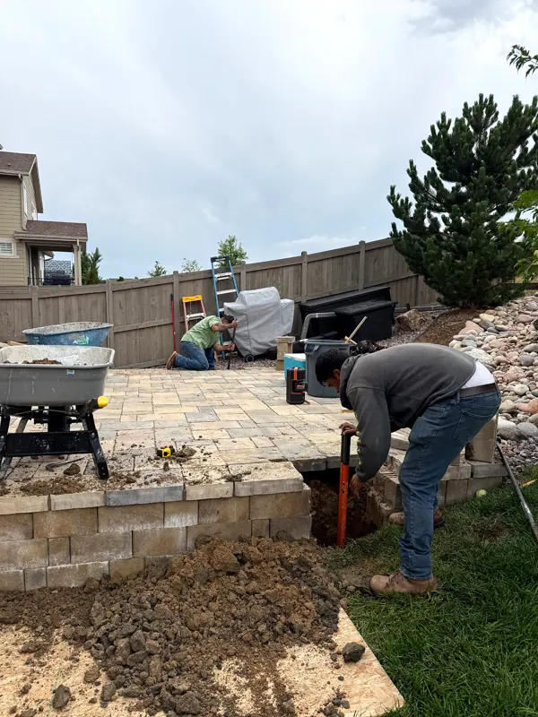 Two workers building a stone retaining edge for a backyard patio