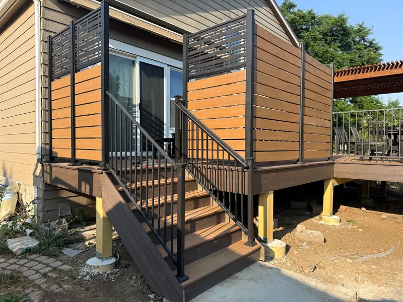 Raised deck stairs with black railings and privacy screens